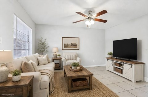 A living room with a white couch, a wooden coffee table, and a flat screen TV.