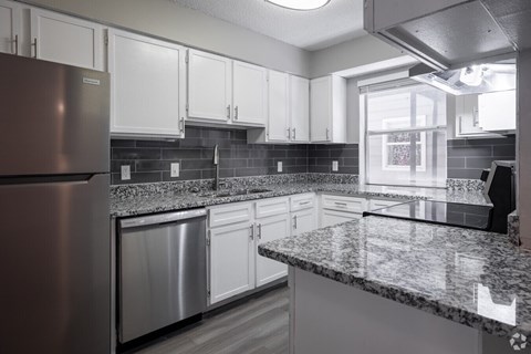 A kitchen with a granite countertop and stainless steel appliances.