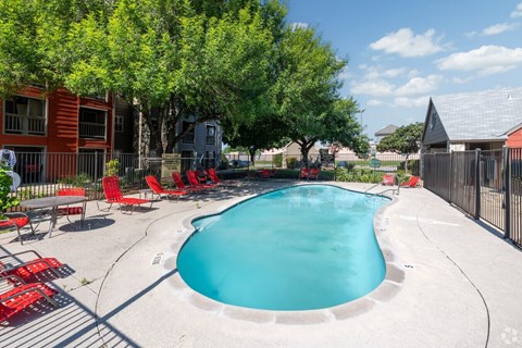 A small pool surrounded by trees and chairs.