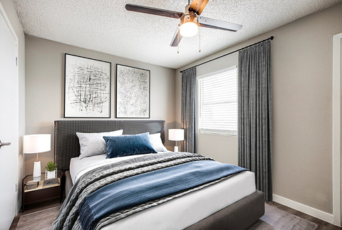 A bedroom with a bed, nightstand, and two framed pictures on the wall.