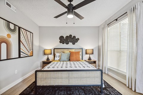 A bedroom with a bed, two lamps, and a ceiling fan.
