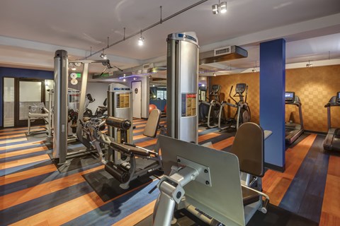 a gym with various machines and weights on a wooden floor