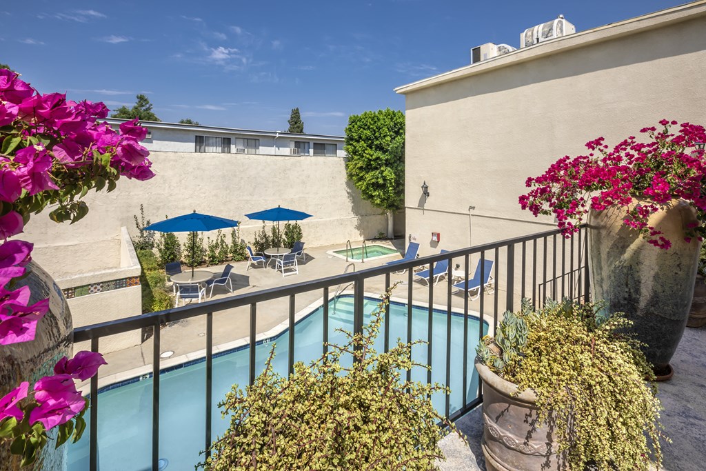 Apartments in Encino, CA - Elevated View of Pool and Patio with Lounge Chairs and Tables with Umbrellas