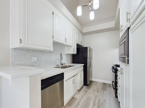 A kitchen with white cabinets and a black refrigerator.