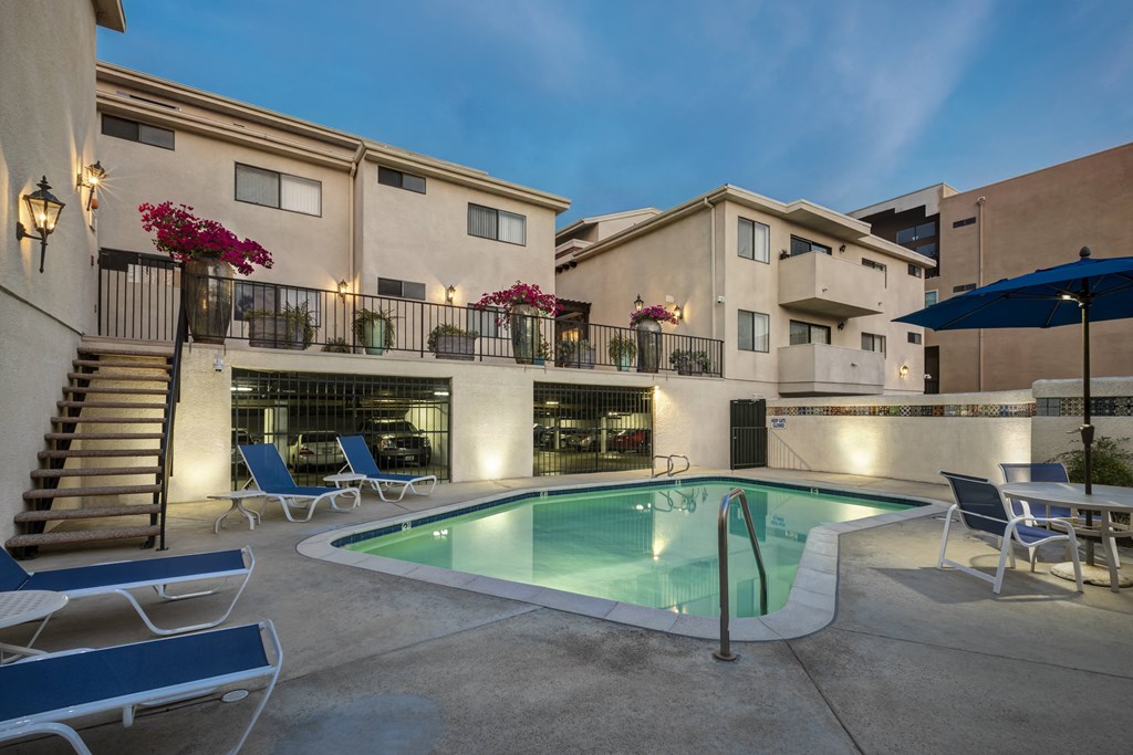 Apartments in Encino, CA - Pool with Lounge Chairs and Building Exteriors Lit Up at Night