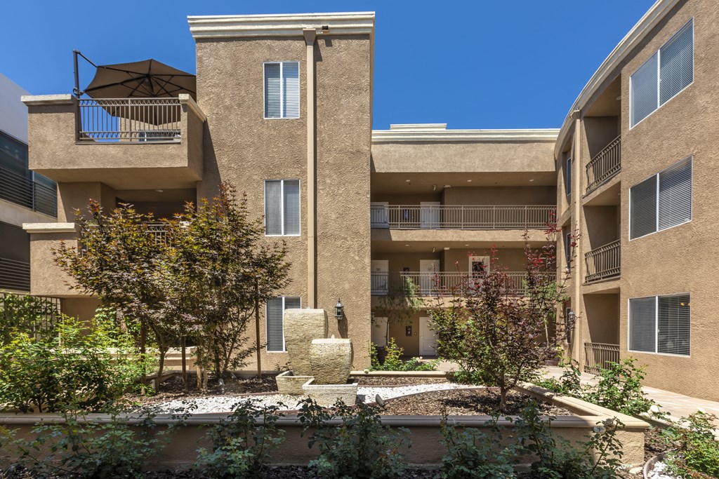 Apartments in Sherman Oaks, CA - Courtyard Art and Foliage with Surrounding Apartment Buildings