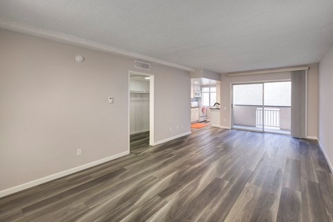 the living room and dining room of an apartment with wood flooring