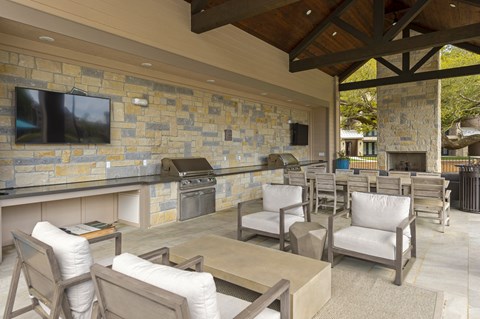 a covered patio with a bar and chairs and a television