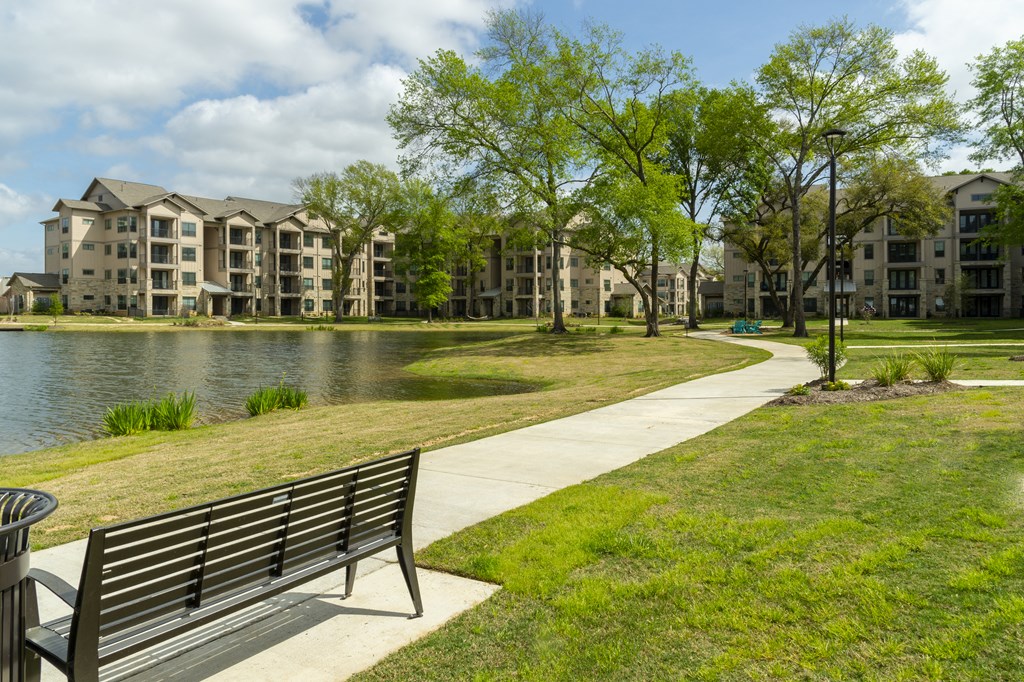 a park bench overlooking a lake with apartments in the background