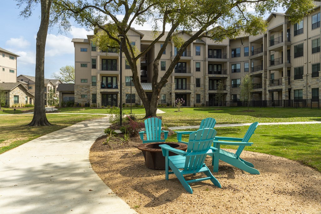two blue chairs sitting on a sidewalk in front of an apartment building