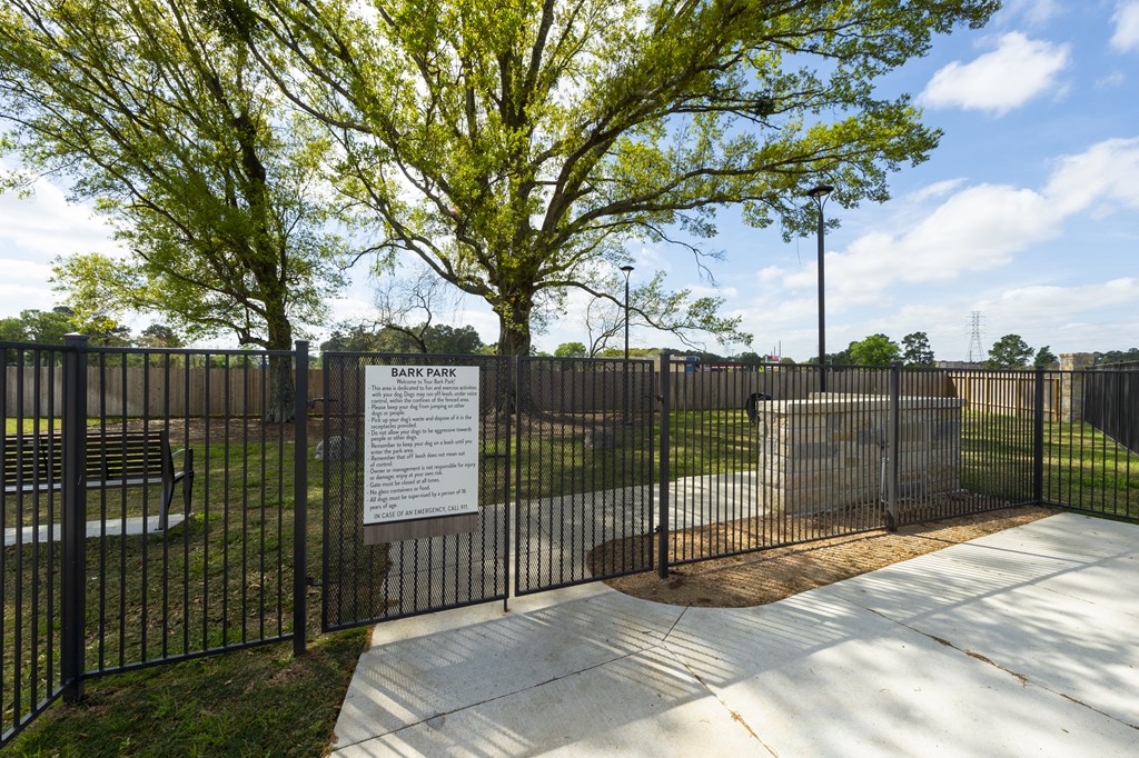 a park with a fence and a sign in front of a tree
