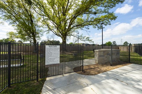 a park with a fence and a sign in front of a tree