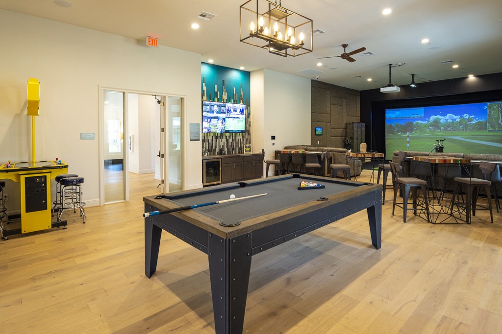 a games room with a pool table in front of a tv