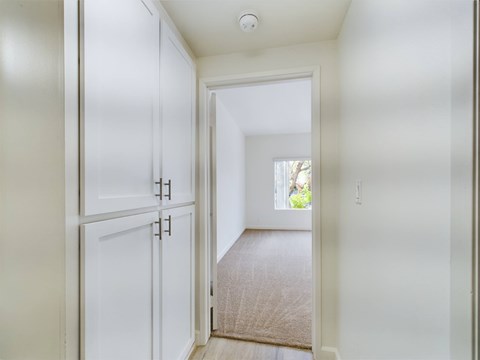 A white hallway with a doorway leading to a bedroom.