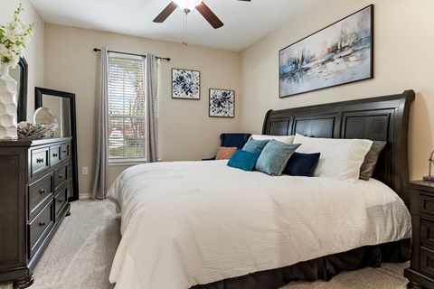 A bedroom with a large bed and a ceiling fan.