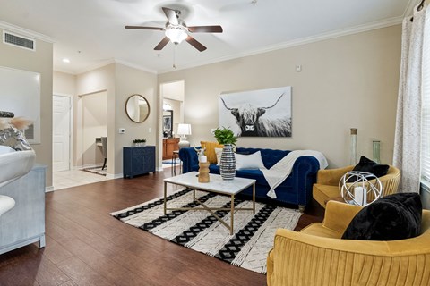 A living room with a blue couch and a painting of a bull on the wall.