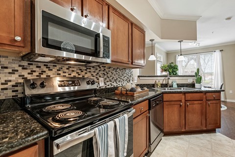 A kitchen with a black stove top oven and a black microwave above it.