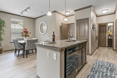 A kitchen with a table and chairs and a counter with a sink and a dishwasher.