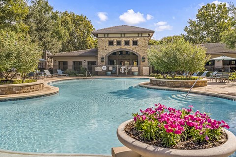 A pool with a building in the background and a flower pot in the foreground.
