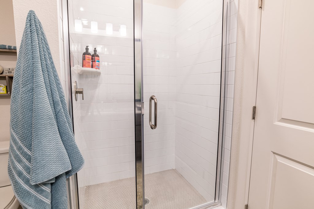 a shower with a glass door and a blue towel in a bathroom