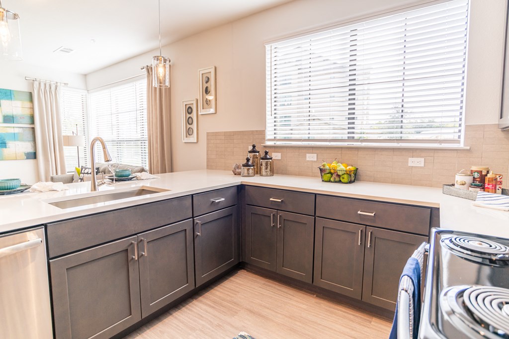 a kitchen with gray cabinets and white counter tops and a stove and sink