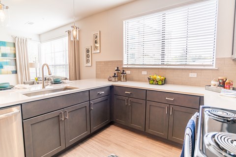 a kitchen with gray cabinets and white counter tops and a stove and sink