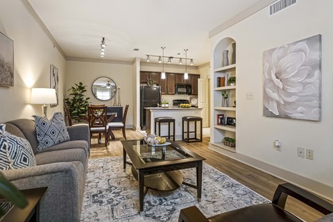 A living room with a grey couch, a coffee table, and a large painting on the wall.