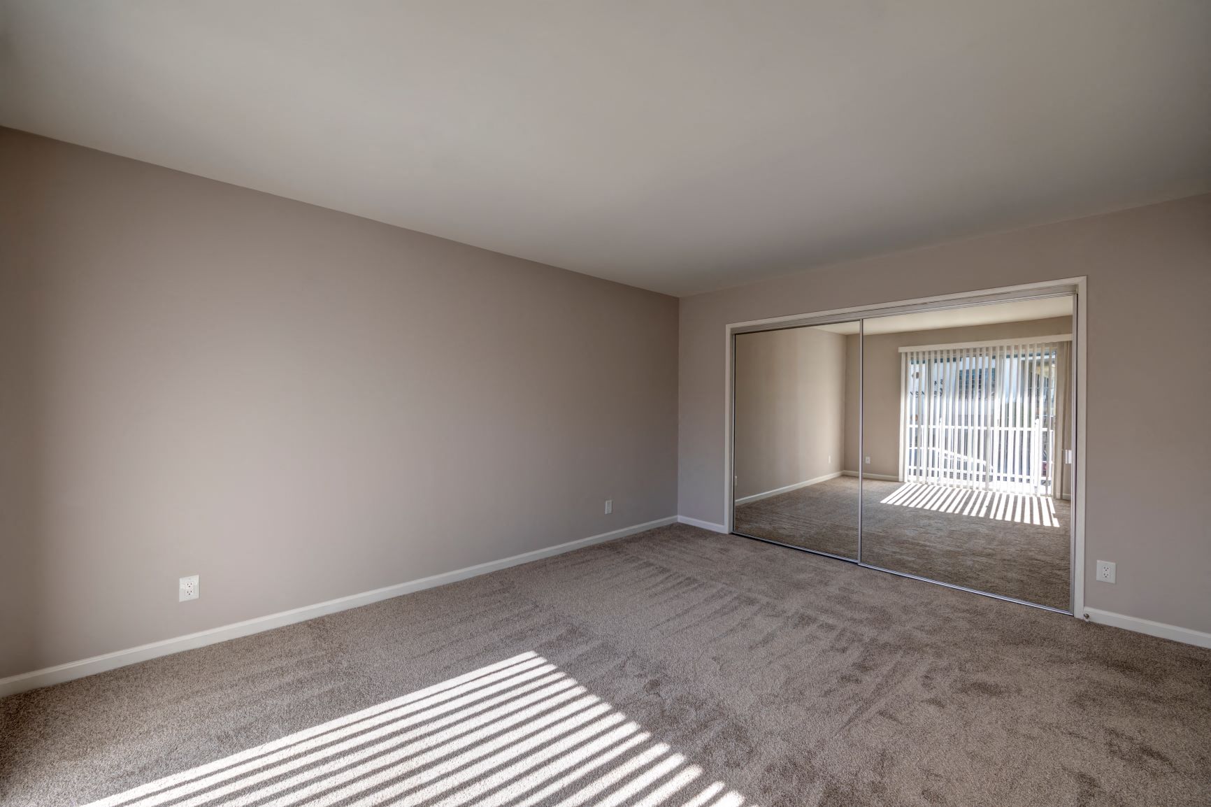 a spacious living room with carpet and a sliding glass door