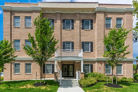 a brick building with a balcony and trees in front of it at Greenway Village Apartments, Metuchen