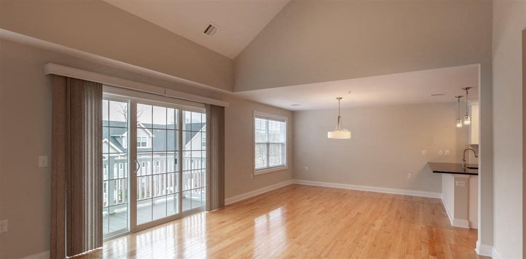 an empty living room with a sliding glass door and a kitchen in the background at Zephyr Ridge Apartment Homes, Cedar Grove, NJ