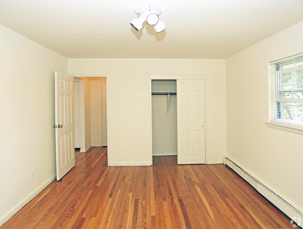 a bedroom with hardwood floors and white walls1 at Willow Gardens Apartments, New Jersey