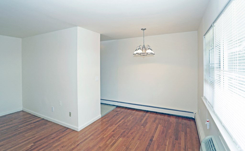 a bedroom with hardwood floors and a chandelier at Willow Gardens Apartments, Teaneck