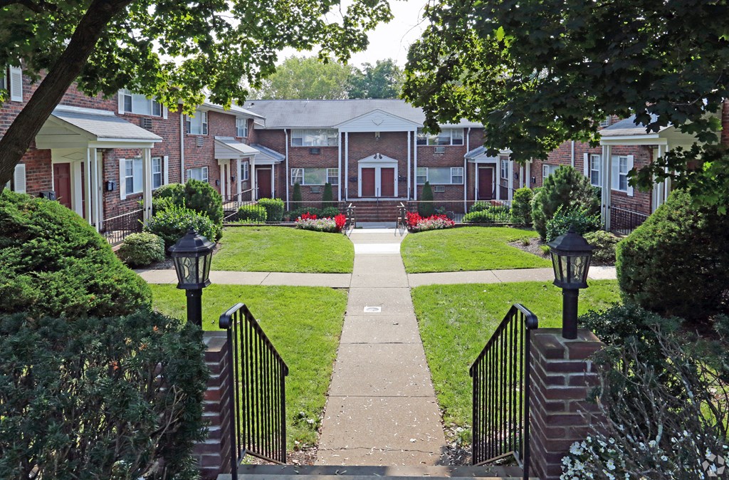 a pathway leading to an apartment complex with red flowers on the lawn at Willow Gardens Apartments, Teaneck