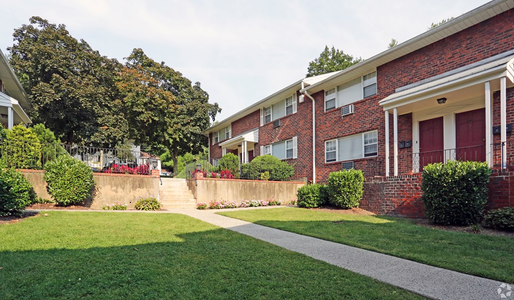 a grassy area with a walkway in front of a brick building at Willow Gardens Apartments, Teaneck, 07666