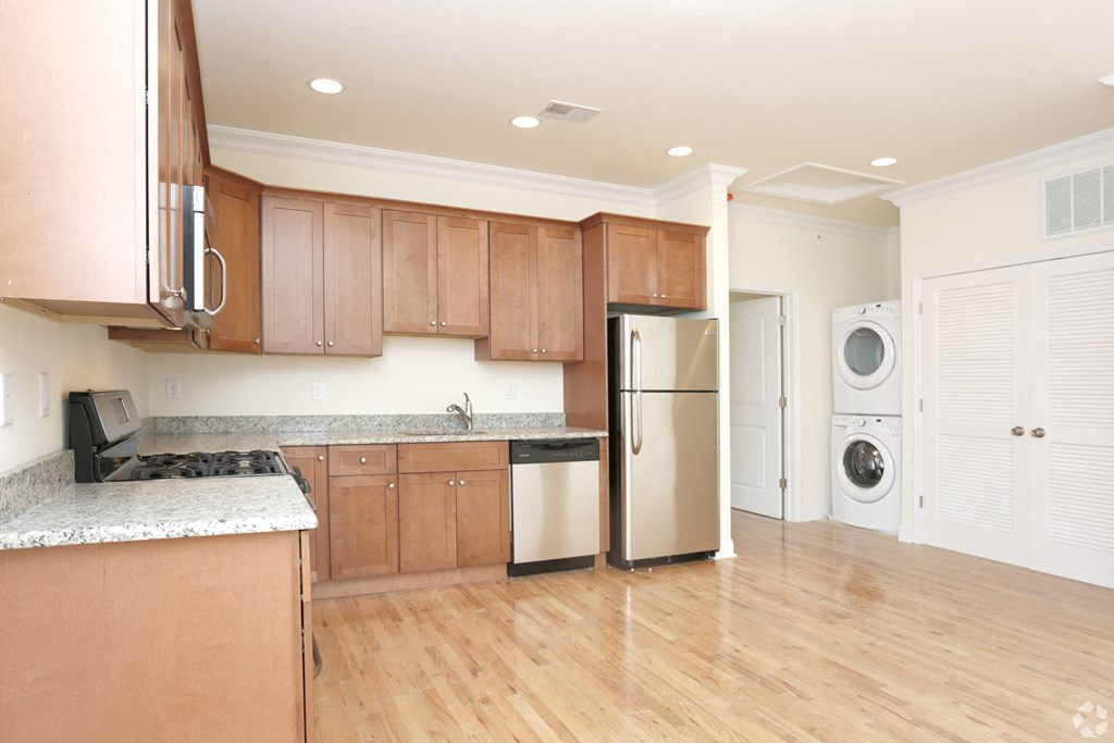 a kitchen with brown cabinets and a white washer and dryer at Greenway Village Apartments, Metuchen, NJ