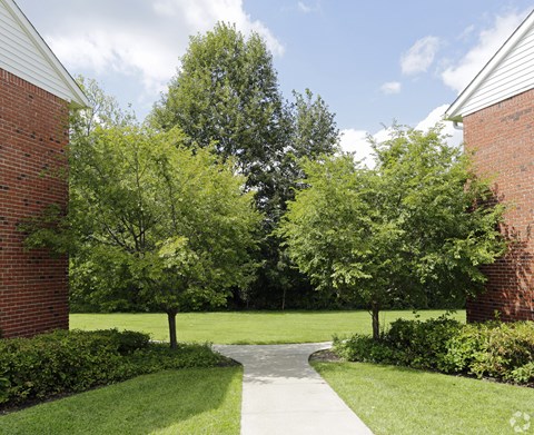a walkway between two buildings with trees in the background at Nottingham Manor Apartments, Montvale, NJ