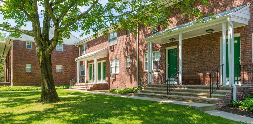 a brick building with green doors and a tree in front of it a brick building with green doors and a tree in front of it at Nottingham Manor Apartments, New Jersey