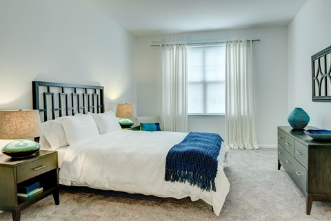 A bedroom with a white bed and a blue blanket.