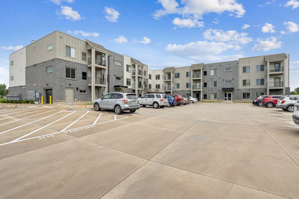 A parking lot in front of a multi-story apartment building.