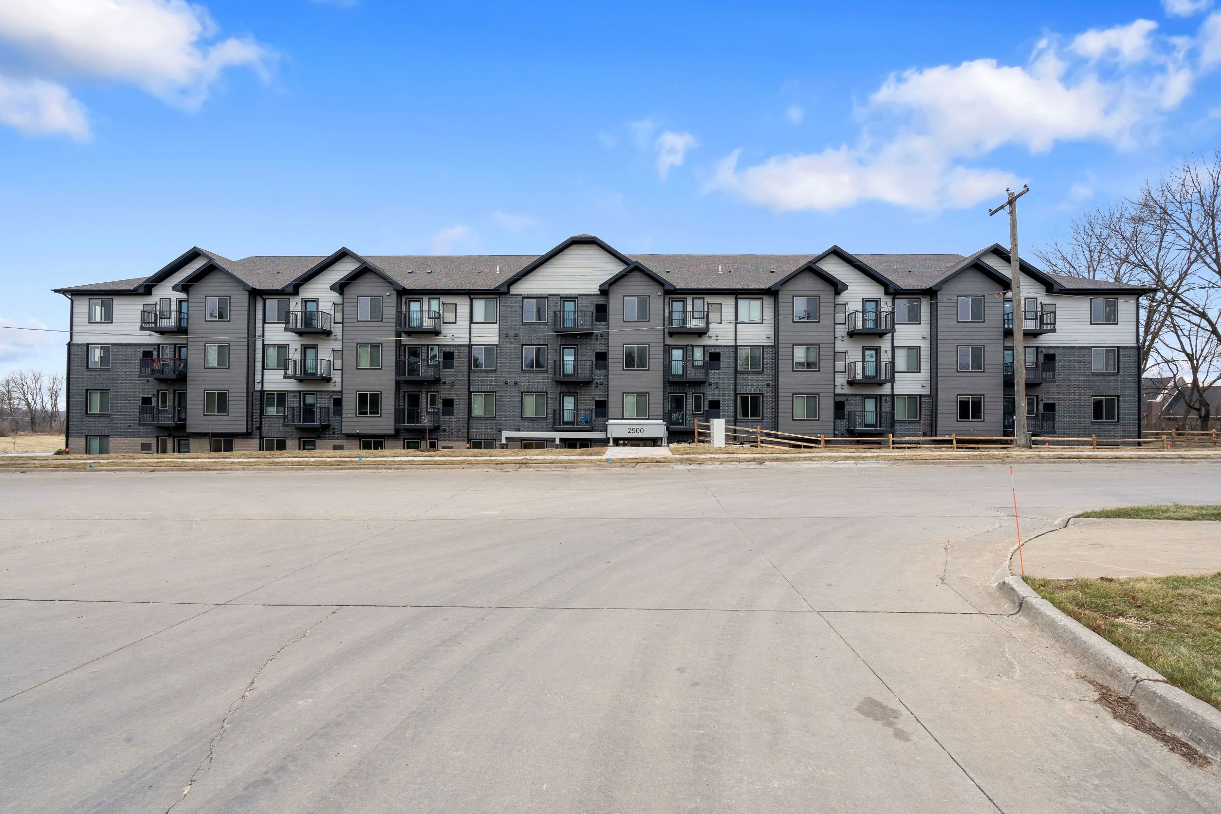A large, modern apartment complex with a parking lot in front.