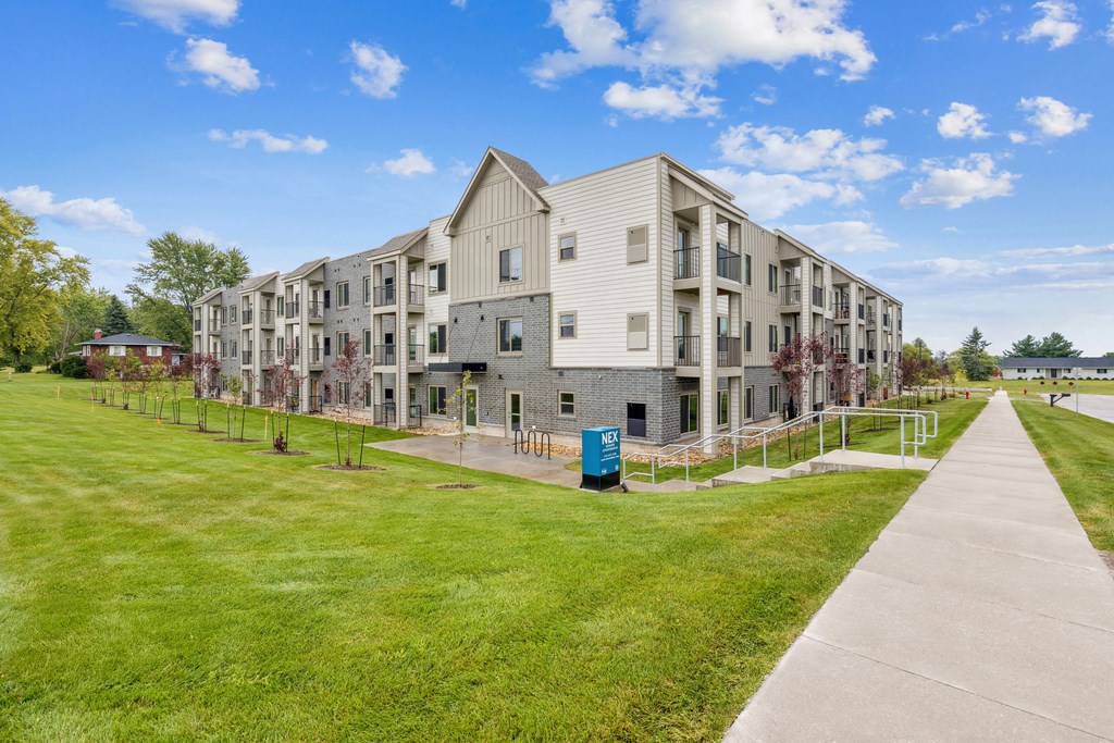 A long building with a green trash can in front of it.