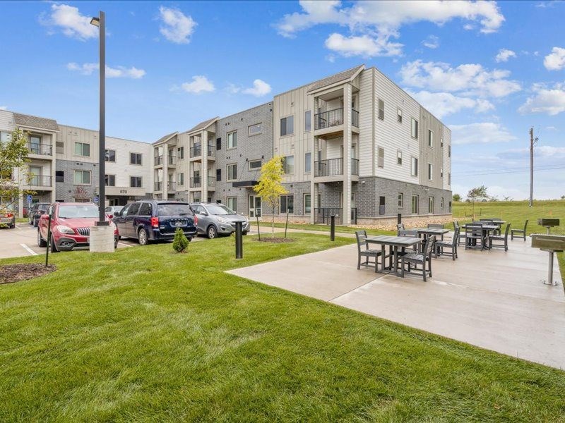 A modern apartment complex with a parking lot and a picnic area.