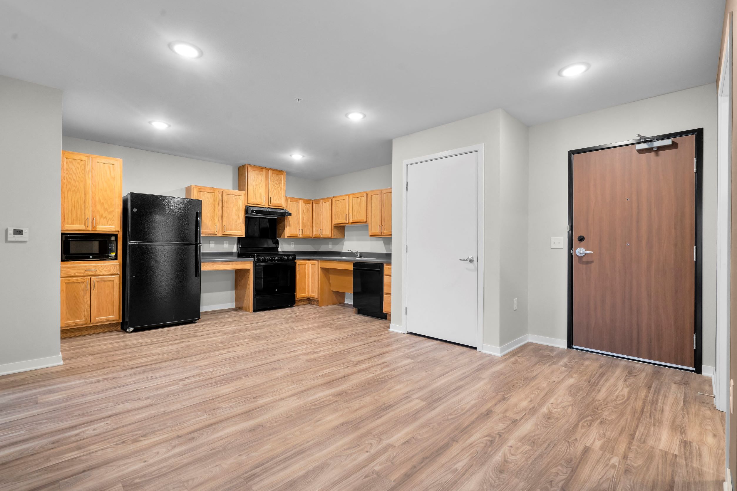 A kitchen with wooden cabinets and a black fridge.