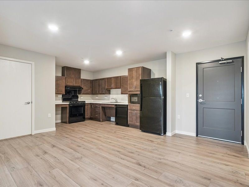 A kitchen with wooden floors and black appliances.