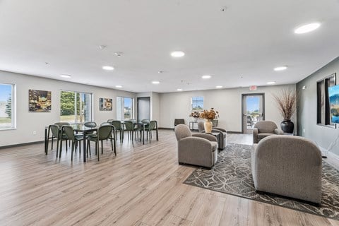 A spacious room with wooden floors and a variety of seating options.