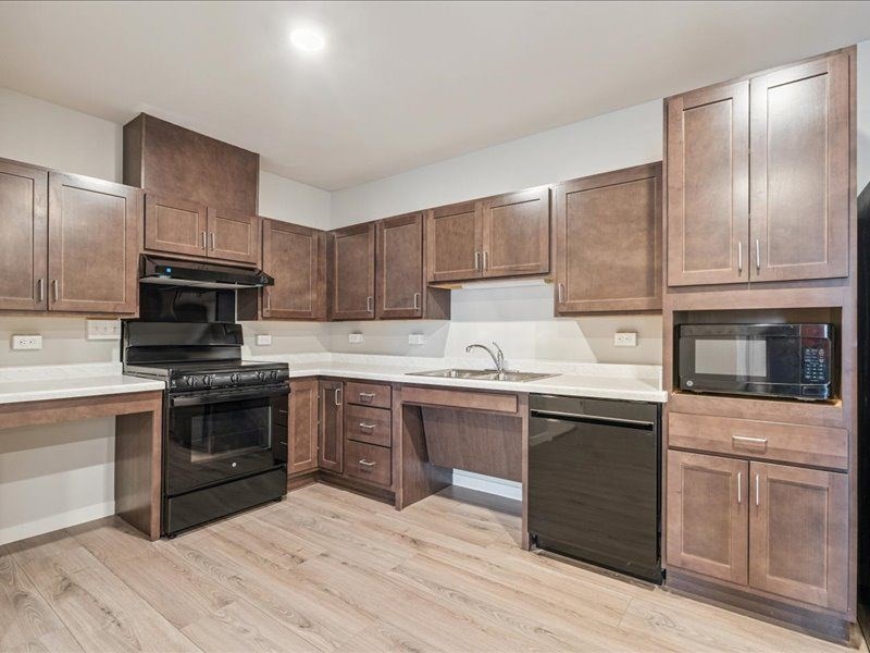 A kitchen with brown cabinets and black appliances.
