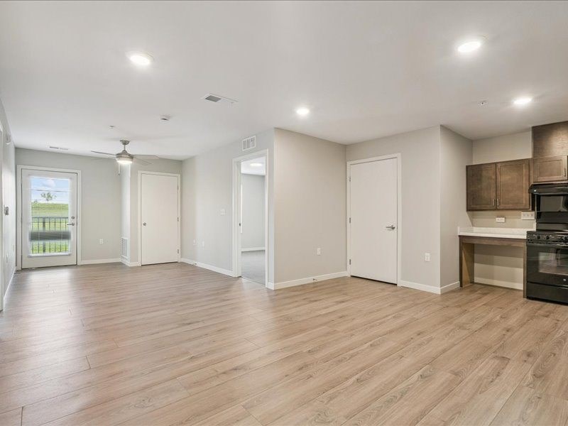 A spacious room with wooden flooring and a kitchenette in the corner.