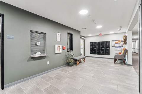 A hallway with a bench, a chair, and a wall with a calendar on it.
