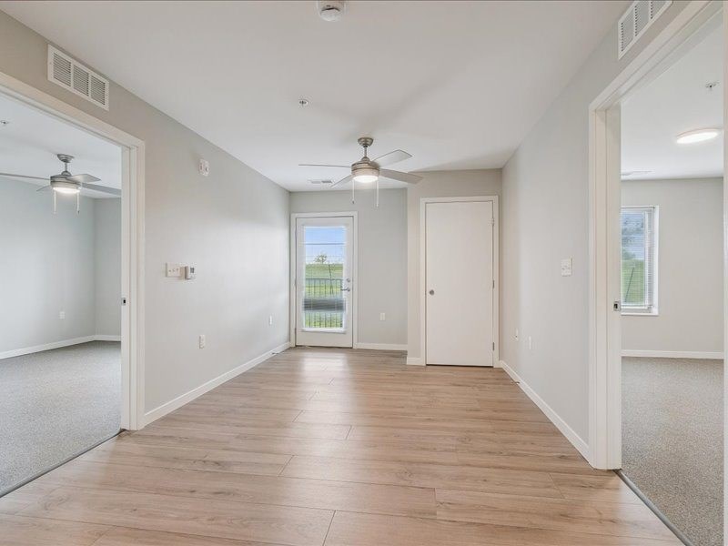 A spacious room with wooden flooring and white walls.
