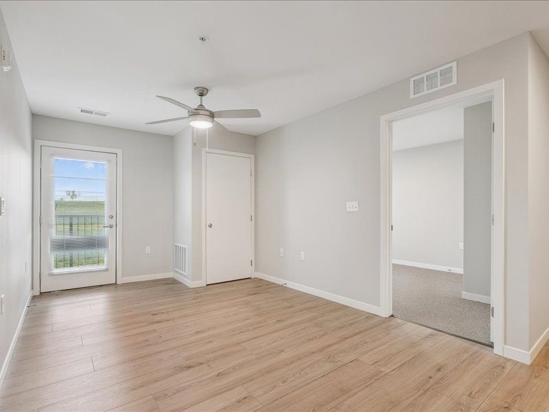 A room with a ceiling fan and a door leading to a balcony.